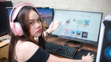A photographic image of a teen with attitude looking very tech-savvy in front of a desktop computer.